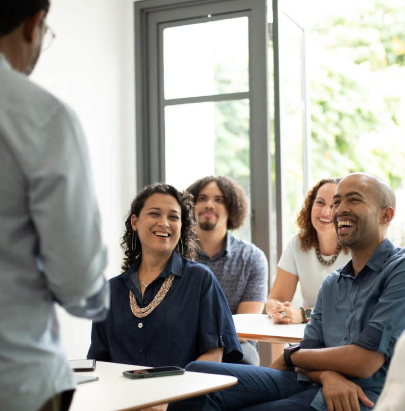 Diverse group of people engaged in animated conversation during a workshop, smiling and connecting authentically